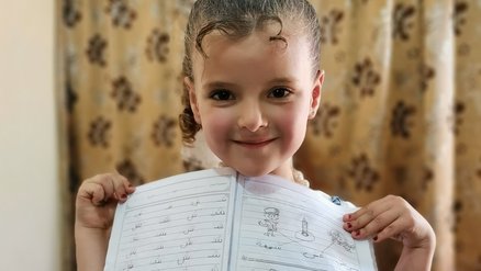 Girl Muna showing a drawing is now continuing education via homeschooling in stead of going to the Safe Space in Jordan_War Child_200820